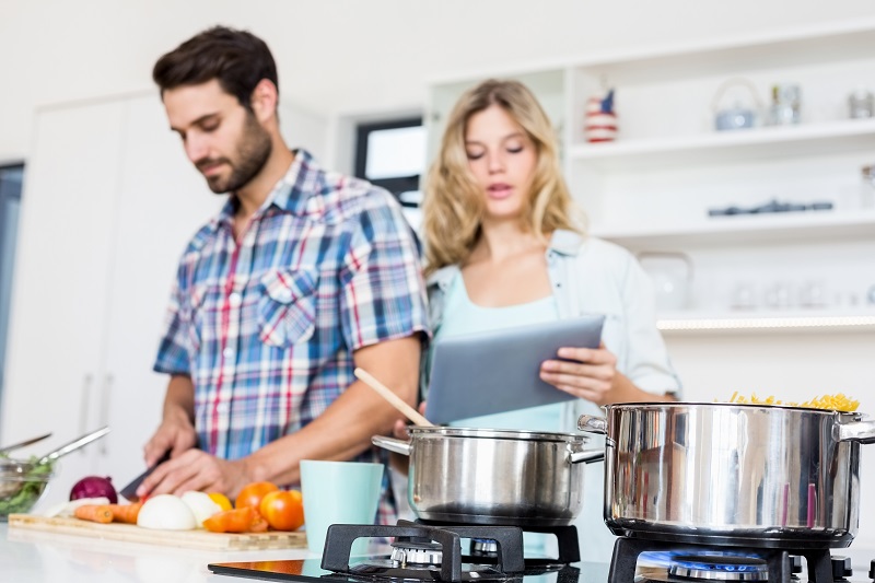 Pareja en la cocina, cocinando espaguetis con gas natural